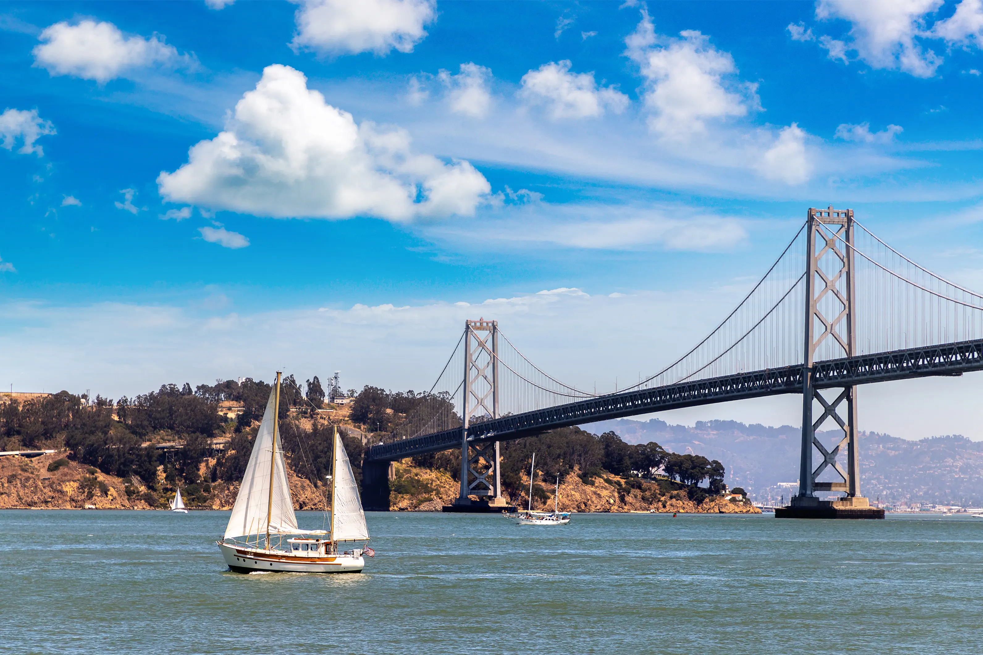 Sailing yacht against Oakland Bay Bridge in San Francisco, California, USA.
