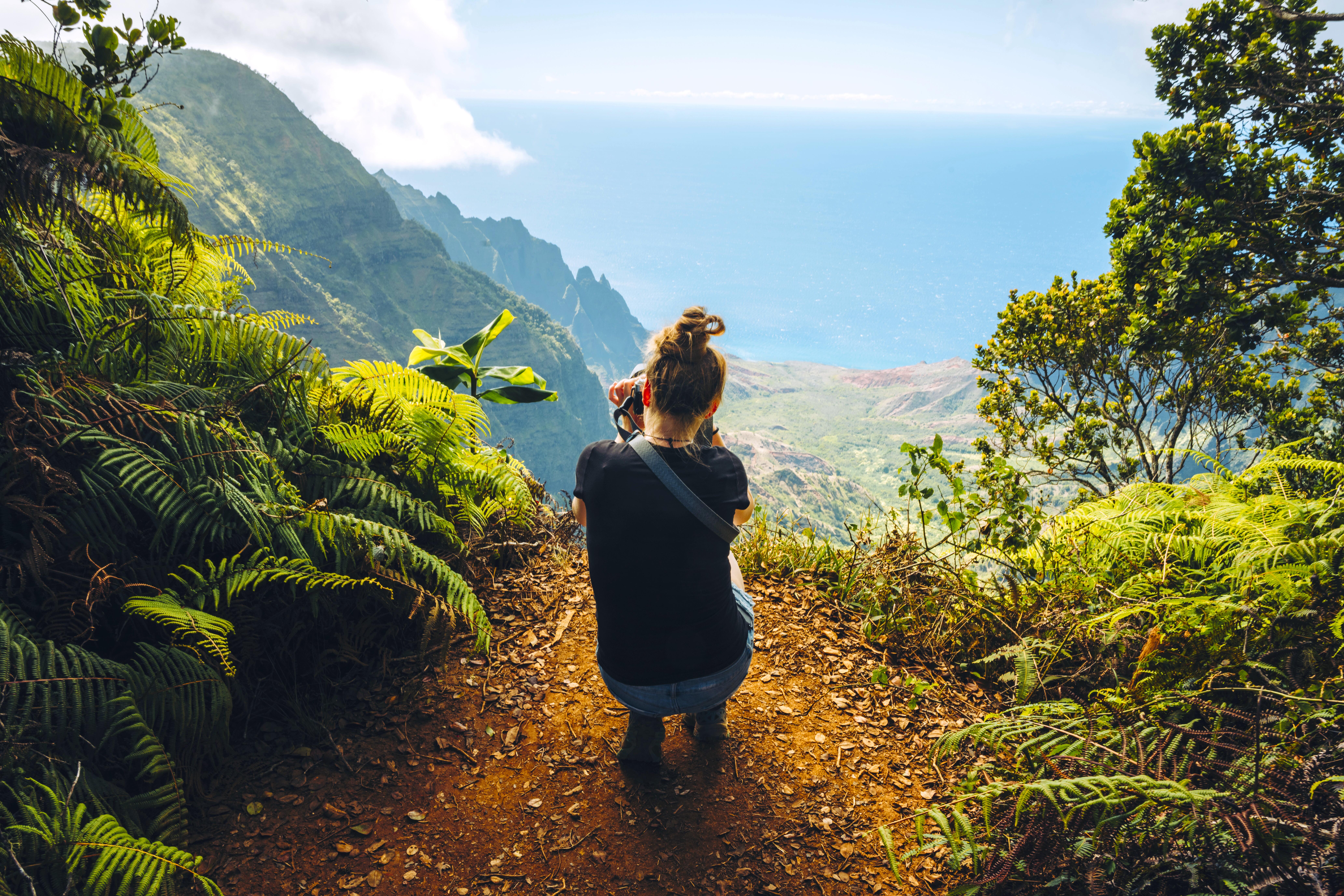Young woman photographing the mountain ridges of the Hawaiian landscape