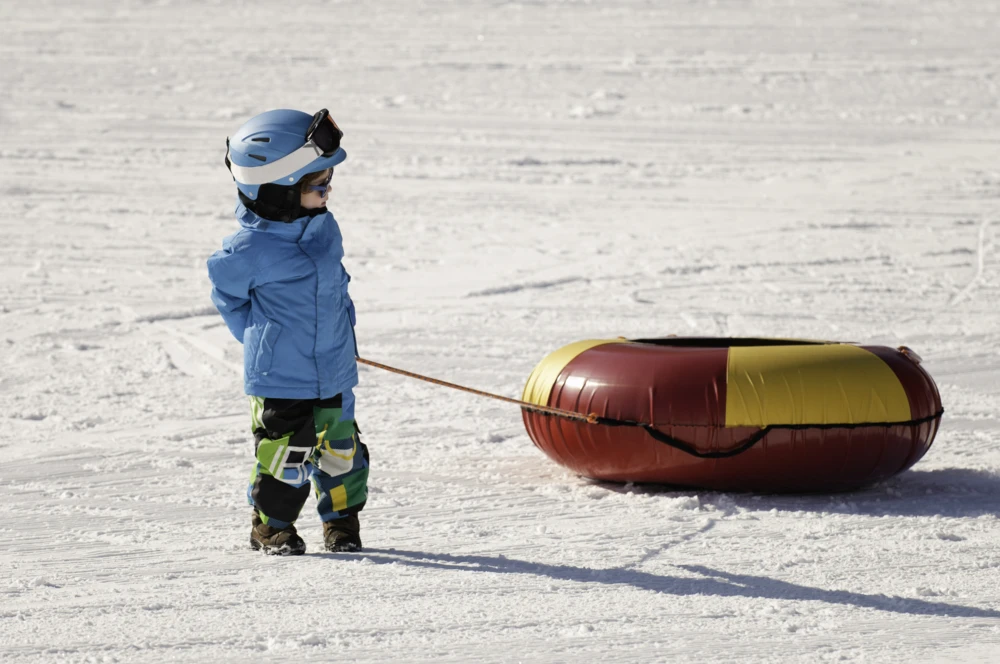 Child towing a snow tube outdoors