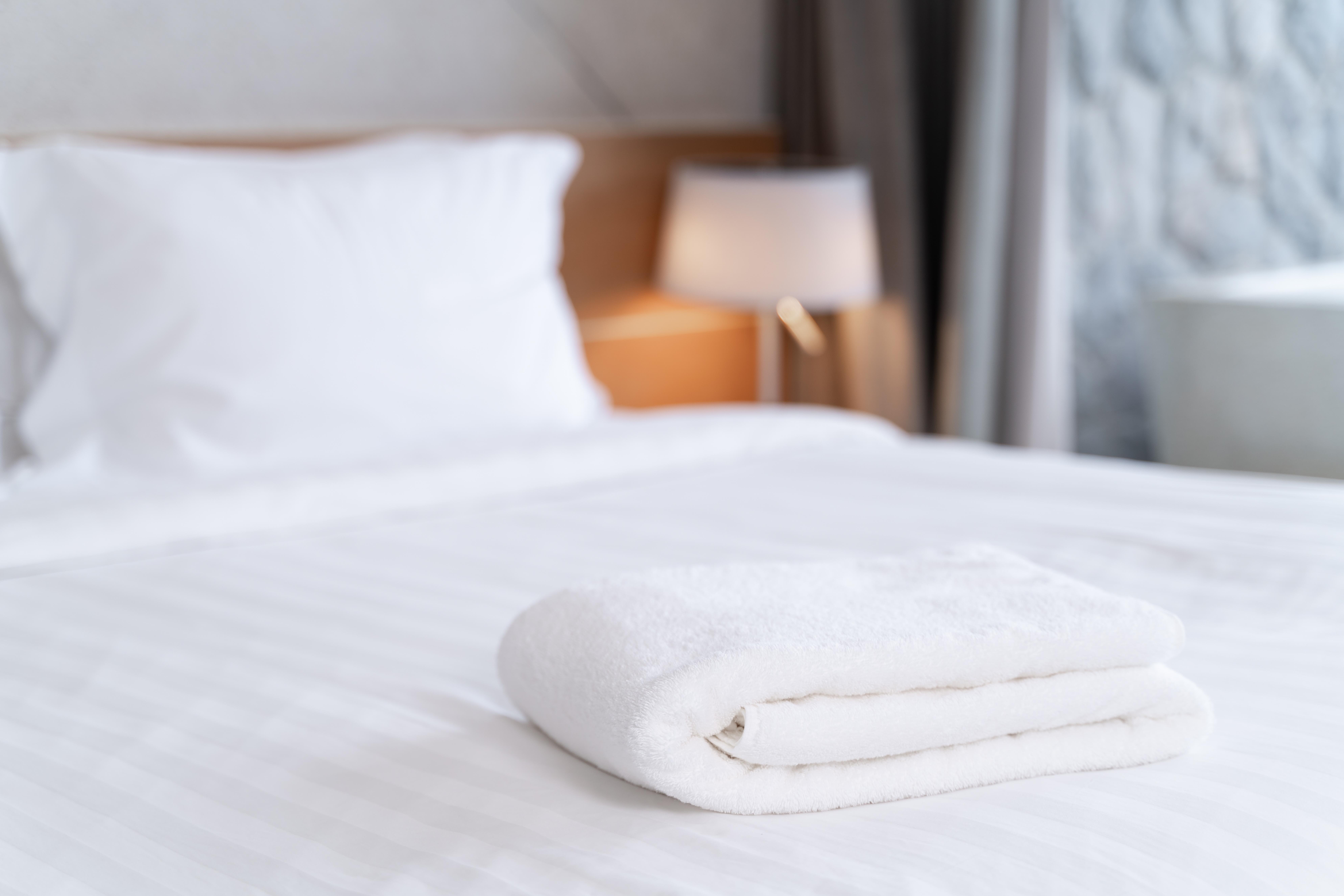 Image of an arranged towel on the bed in a hotel bedroom.