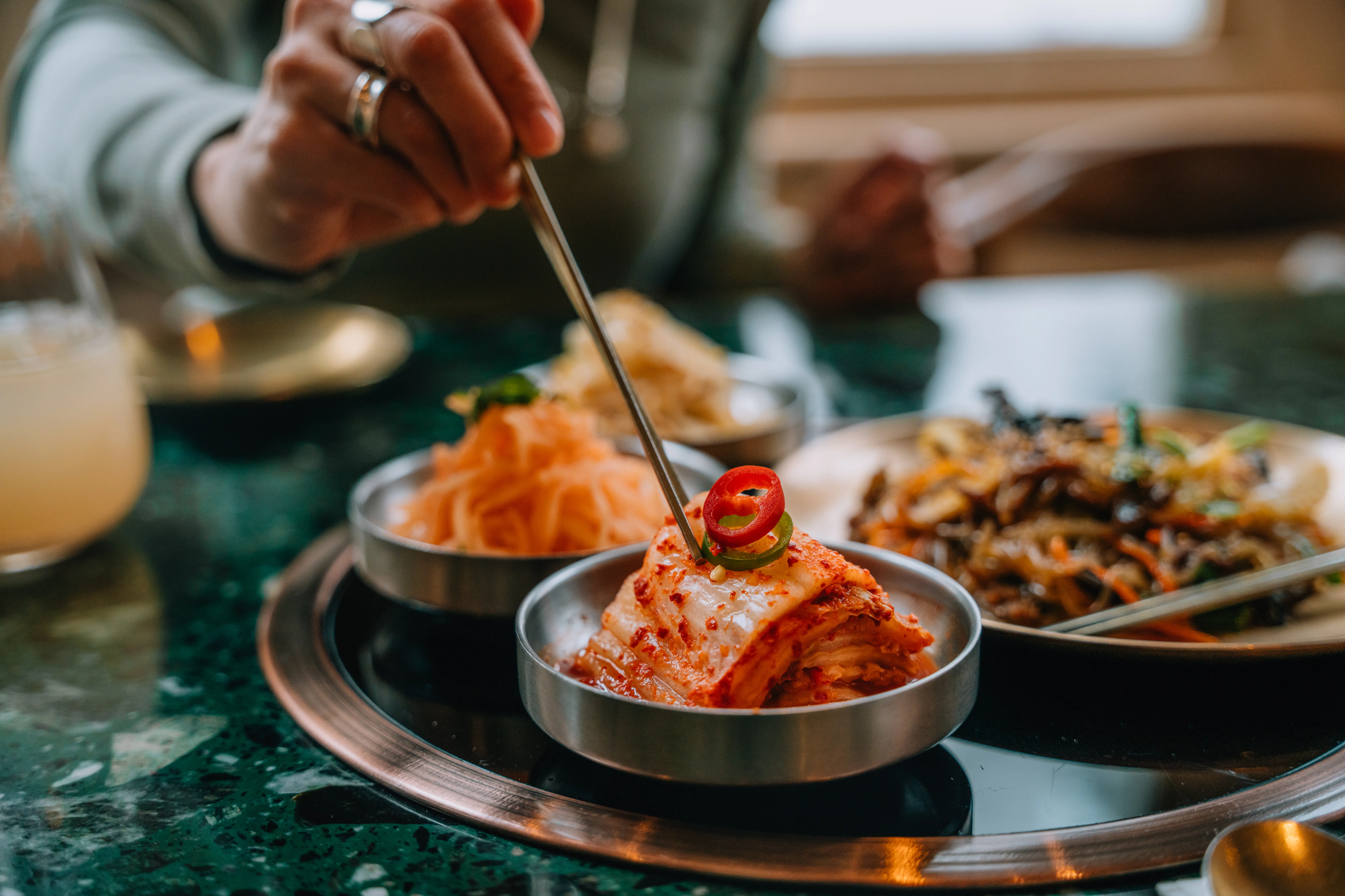 Closeup image of a woman eating Kimchi with chopsticks in Korean restaurant.