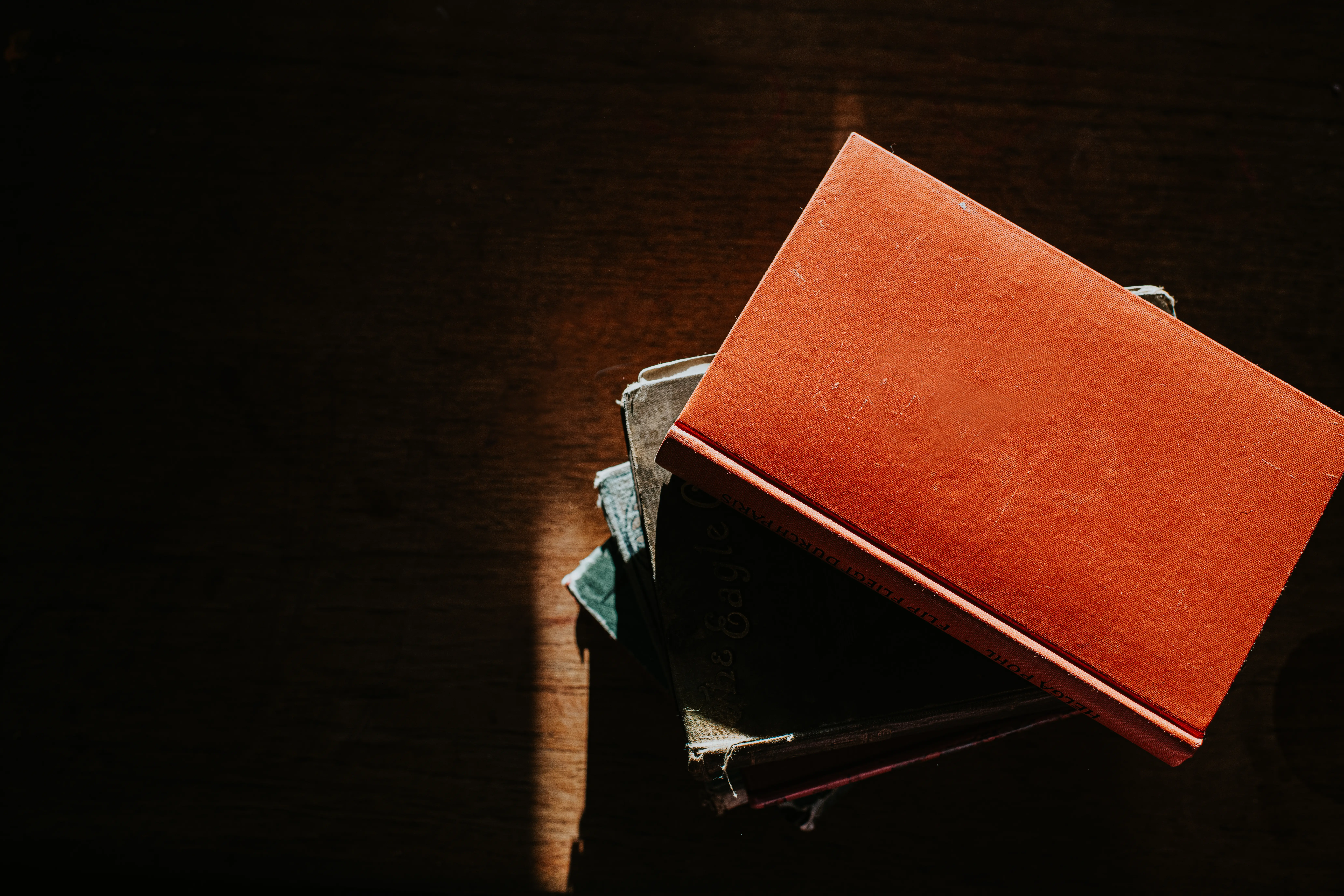 Overhead image of a stack of books on a wooden table.