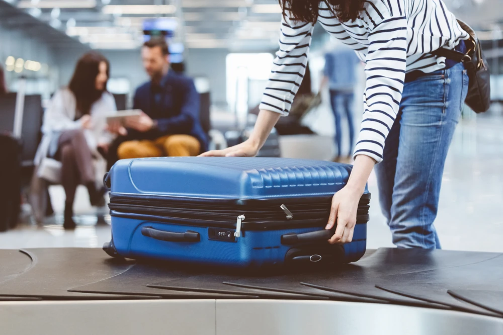 Female traveler picking up suitcase from baggage claim