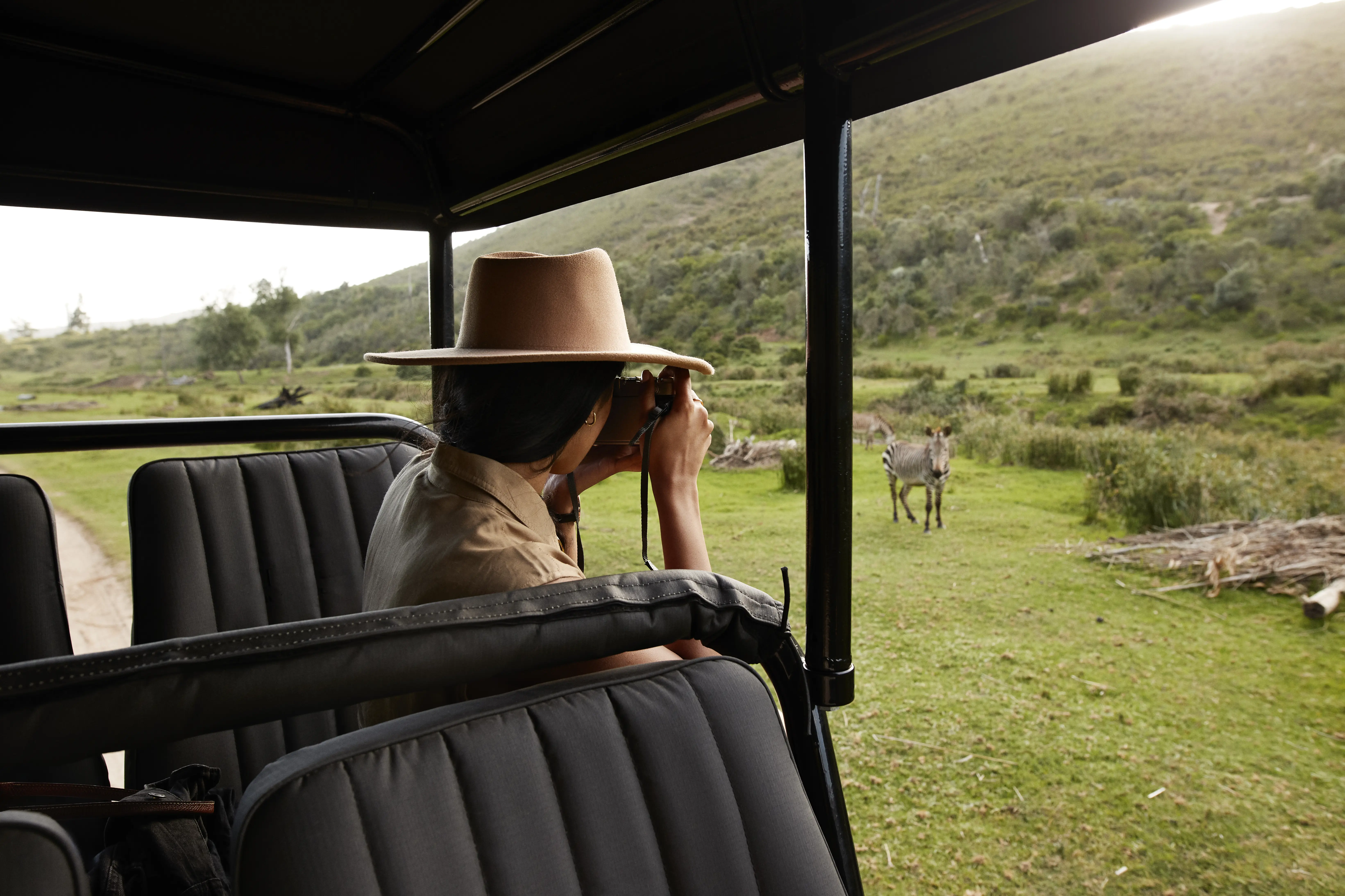 Image of a woman observing a zebra while on a safari.