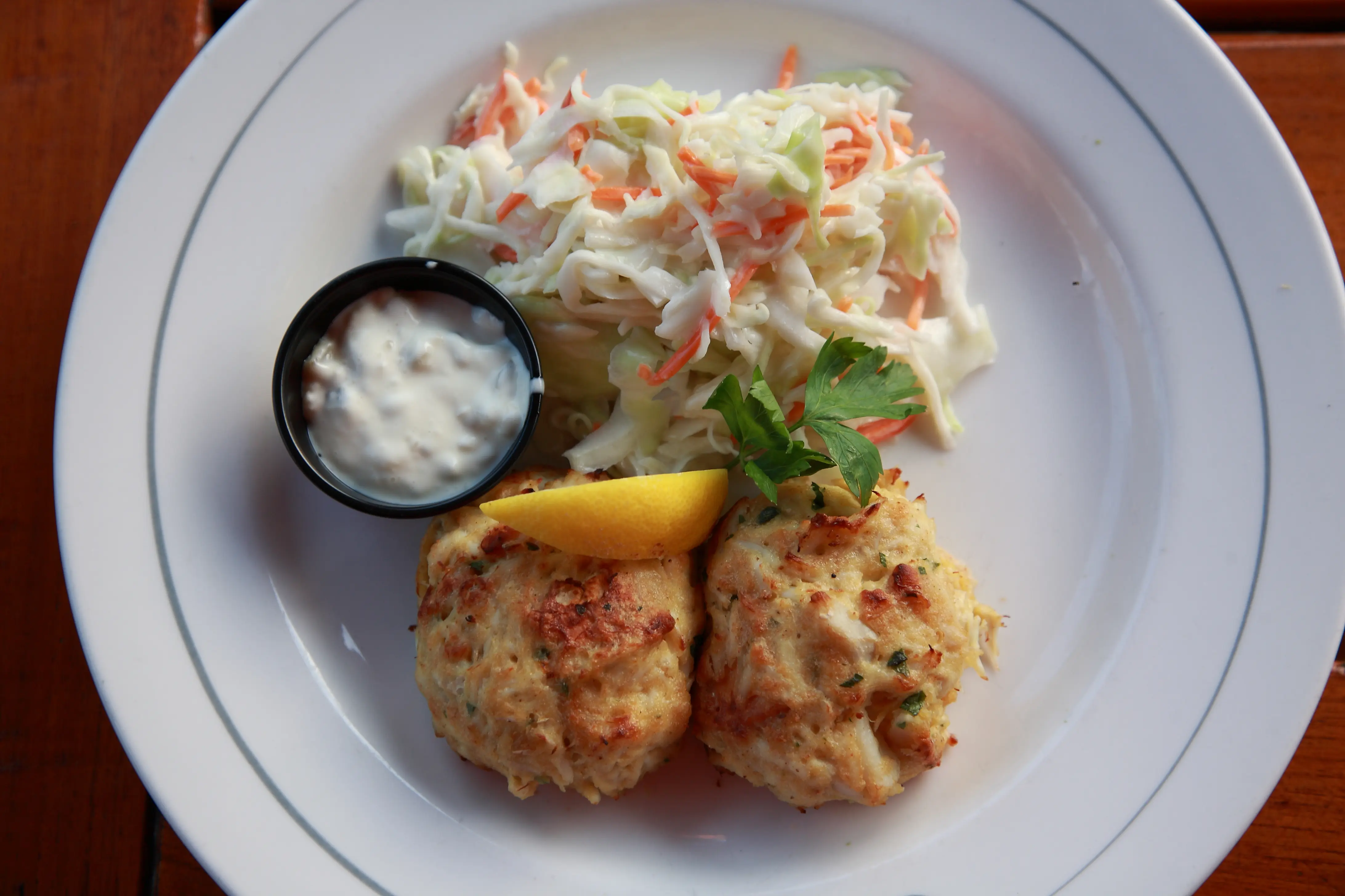 Maryland Crab Cakes with salad and tartar sauce on table from a famous restaurant at inner harbor in Baltimore, USA