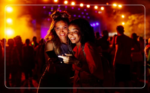 Photo of two people looking at a phone at a live entertainment venue.