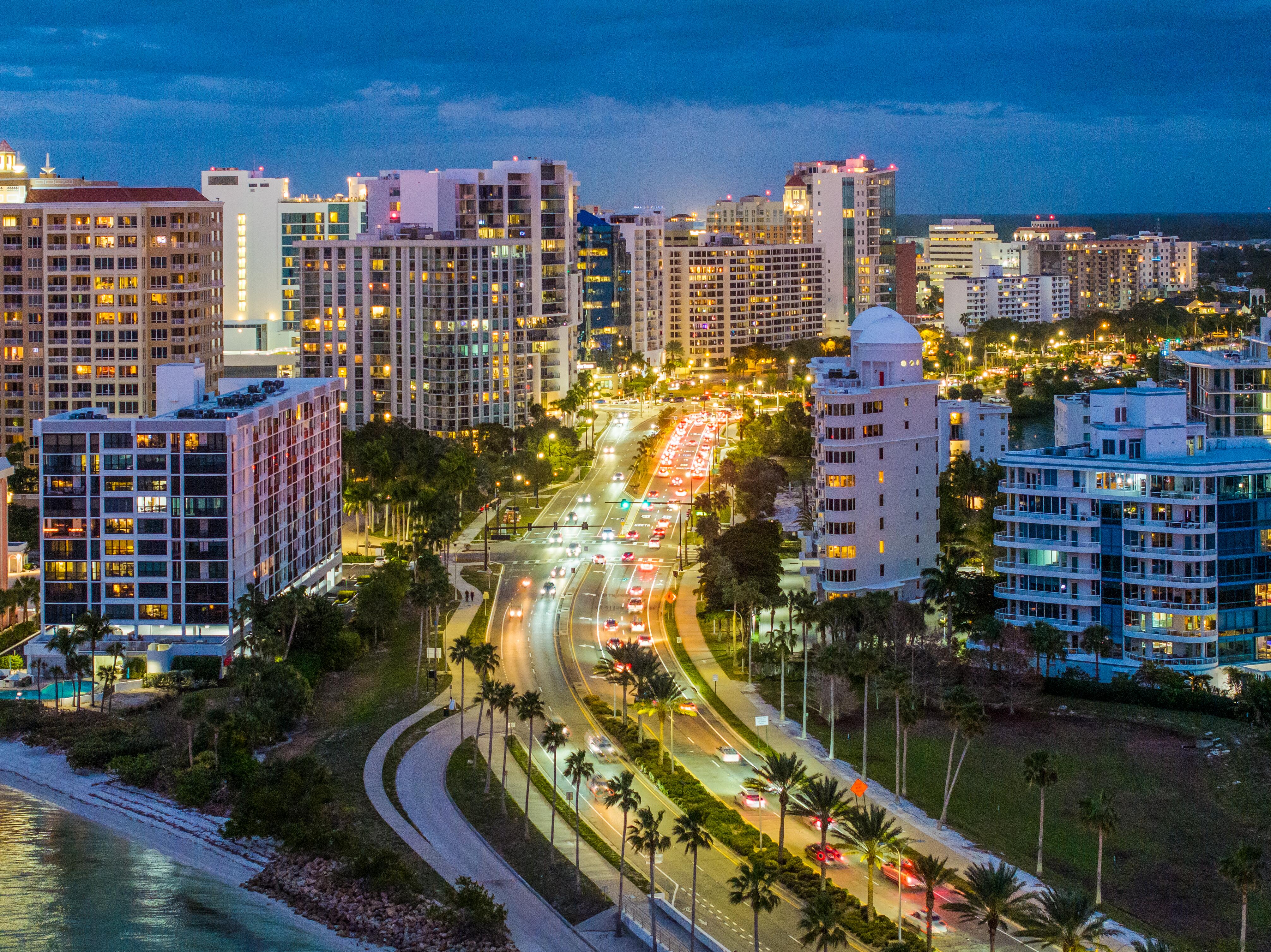 Sarasota Skyline at night from drone point of view with colorful lights and street traffic