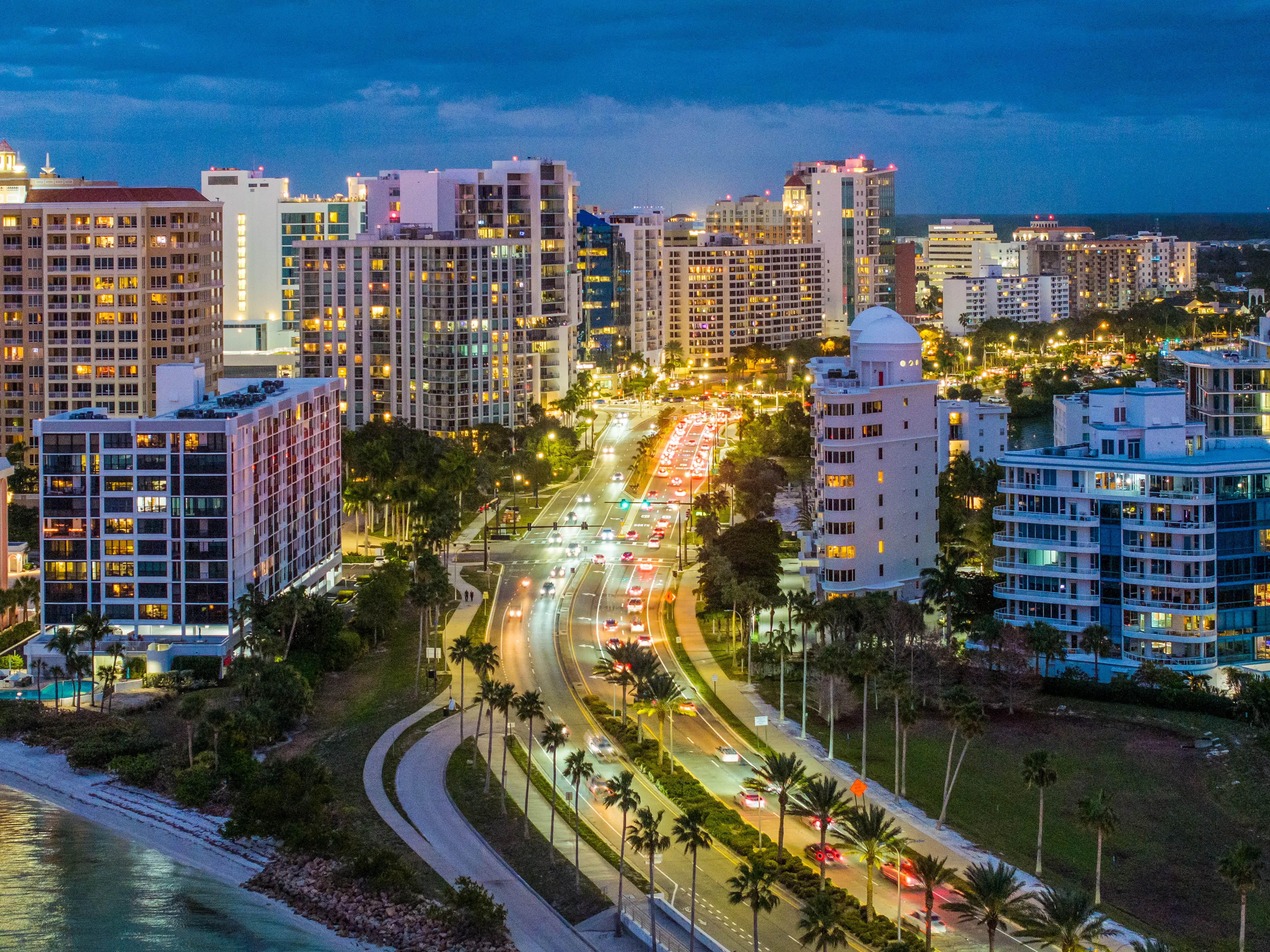 Sarasota Skyline at night from drone point of view with colorful lights and street traffic
