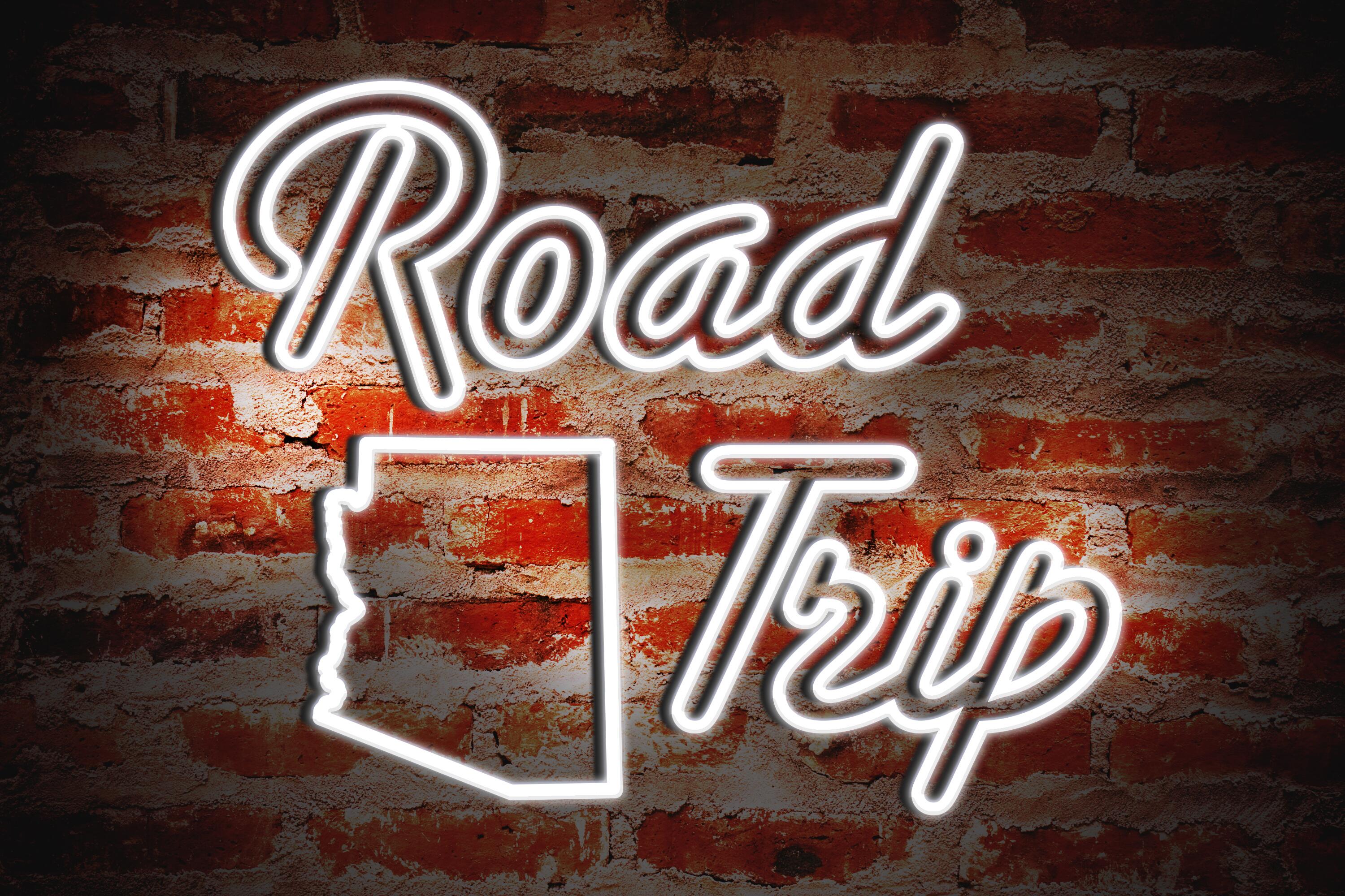 Arizona Road Trip sign in neon on red brick background