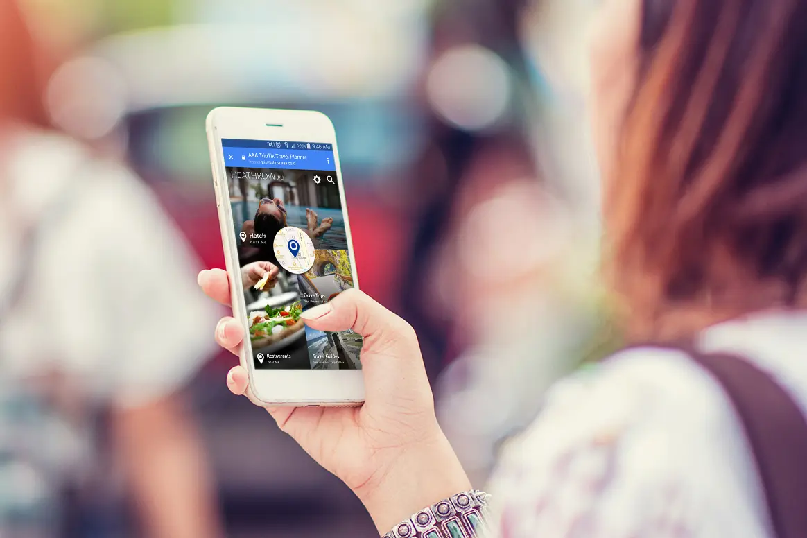 Woman searching for hotel on smartphone within AAA mobile app.