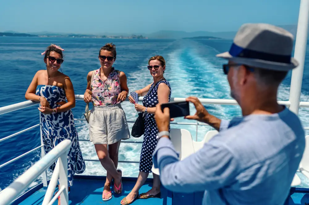 Man taking picture of three women, all standing on the deck of a cruise ship
