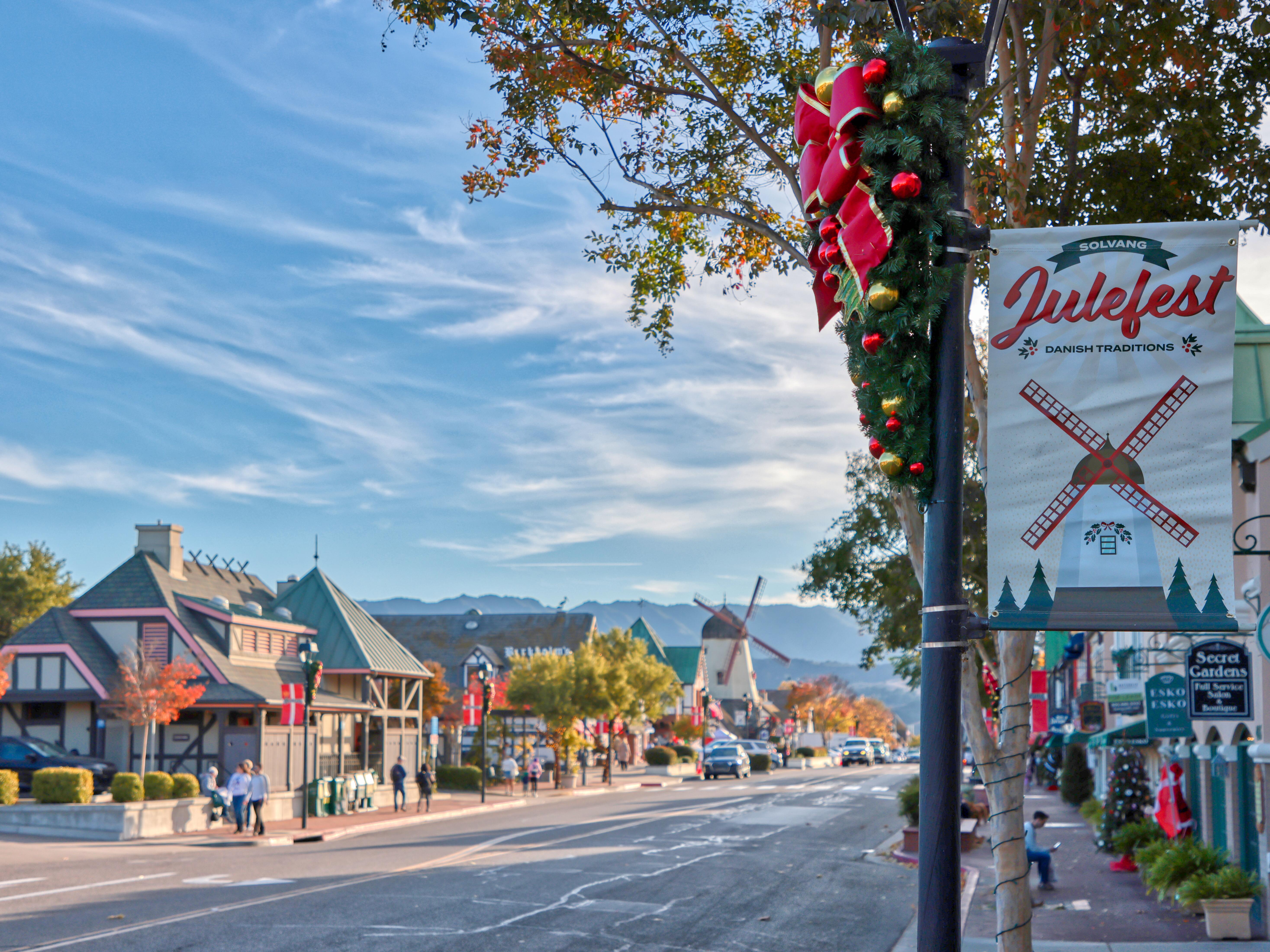 Solvang Julefest sign on light post with Bavarian-style buildings lining the street.