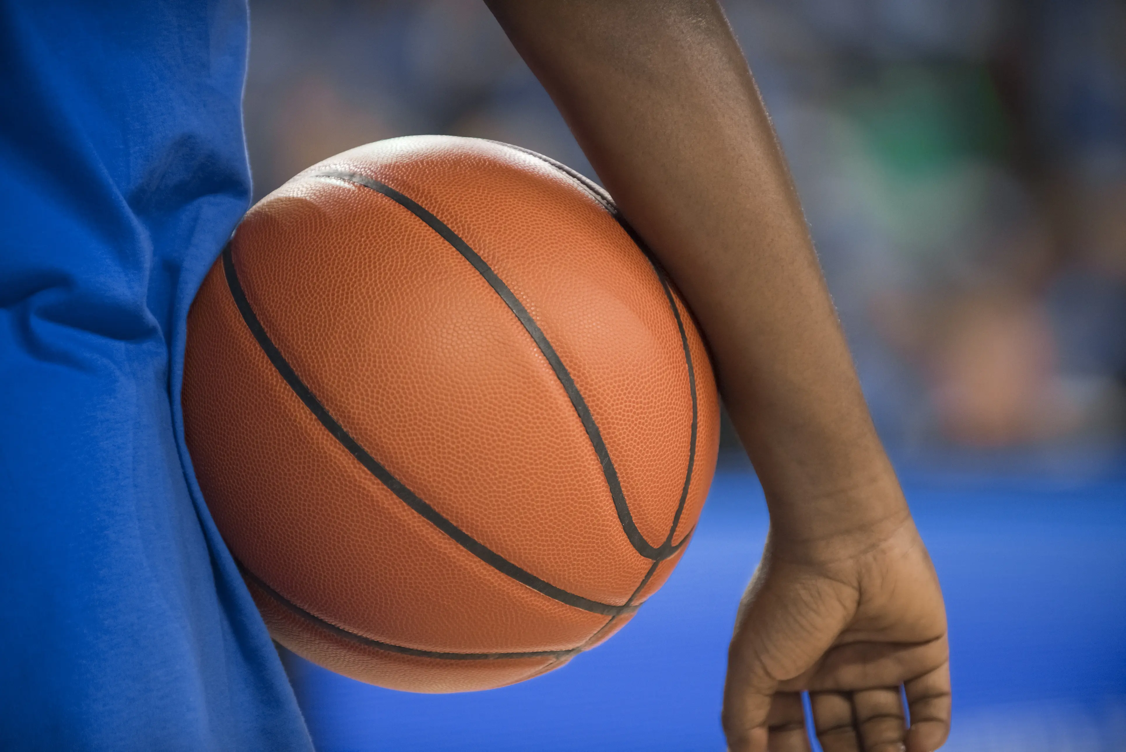 Close-up of basketball player in blue standing with basketball