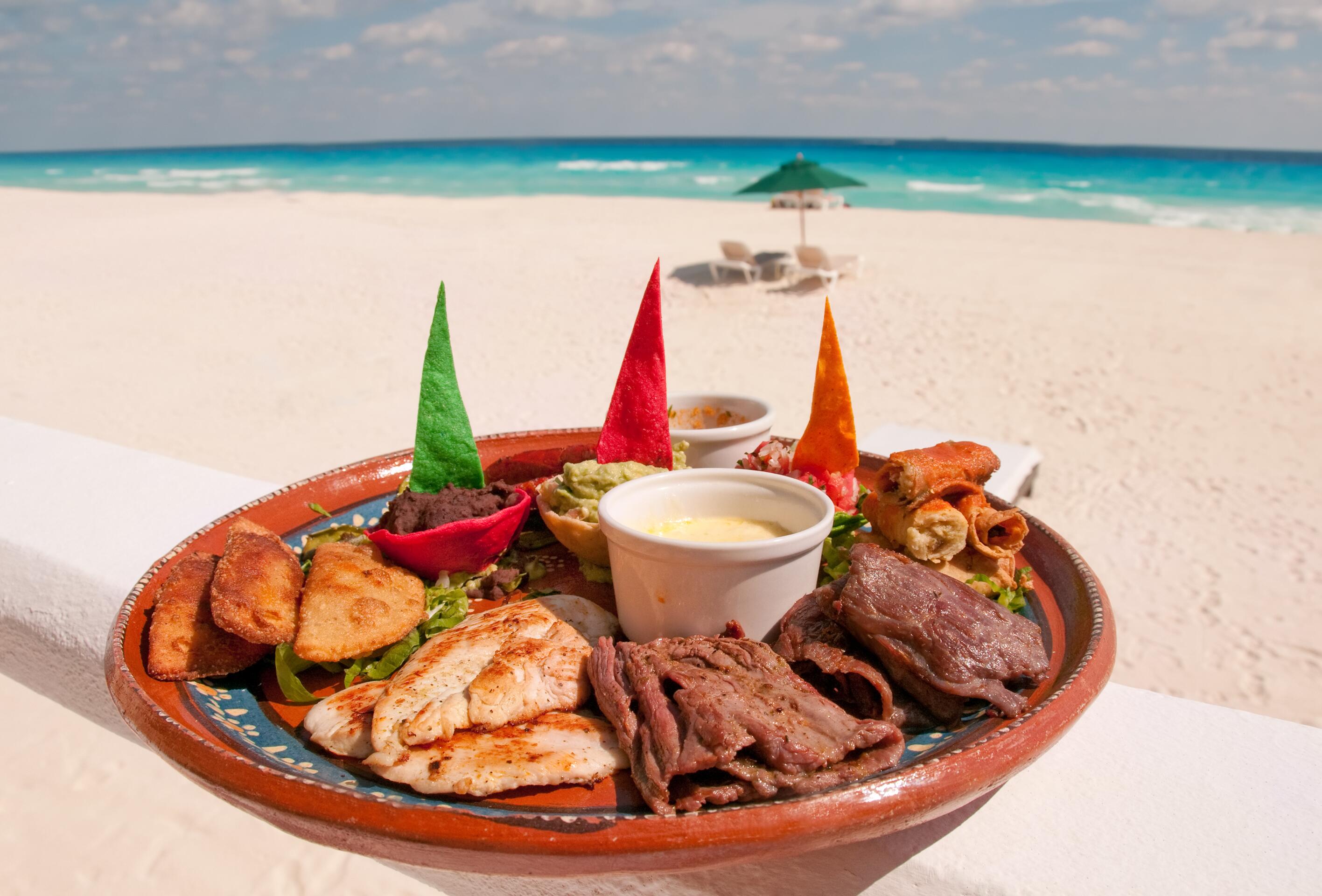 A plate of authentic Mexican food served up al a carte on the beach with ocean in the background