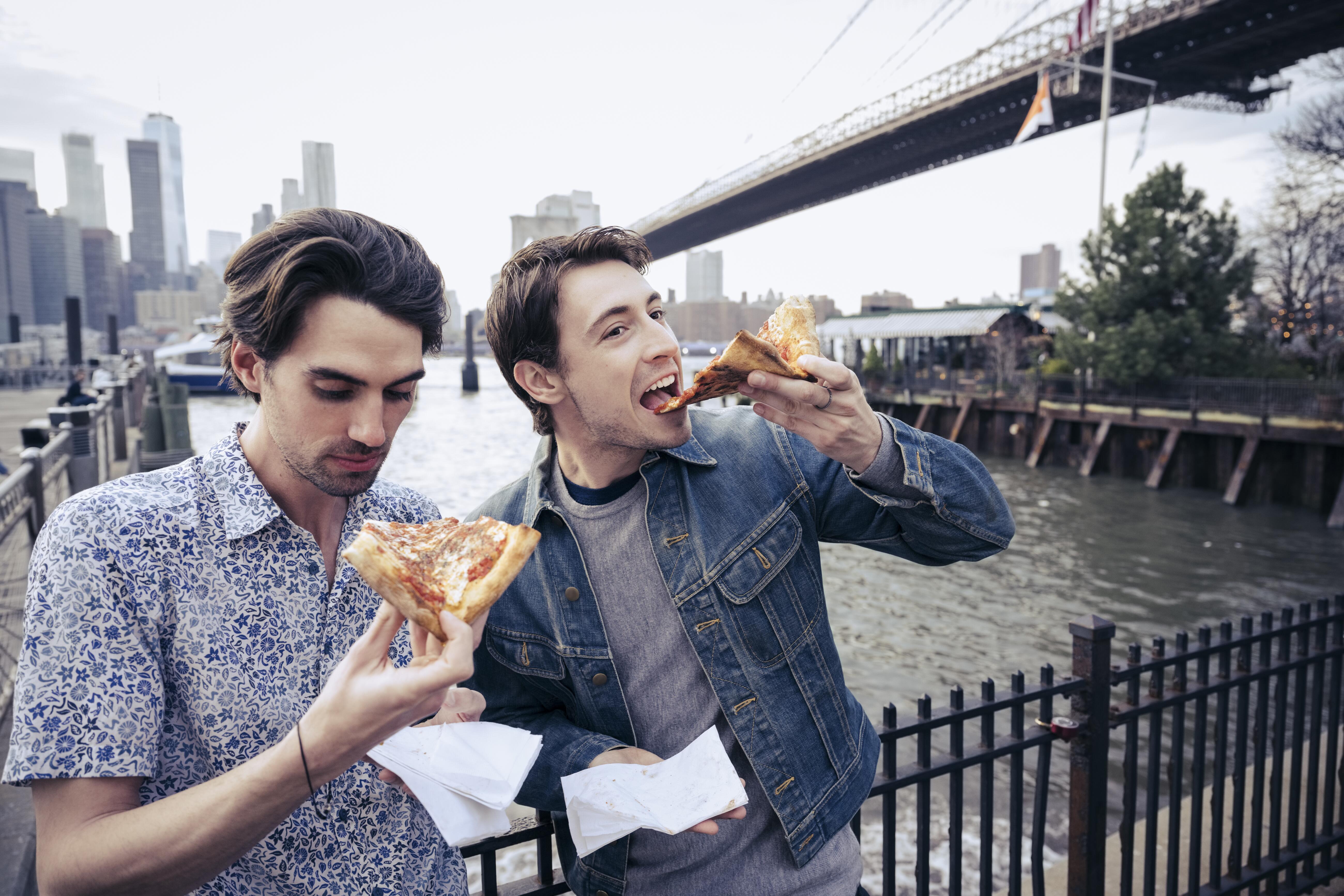 Image of two guys eating slices of pizza in Brooklyn, New York.
